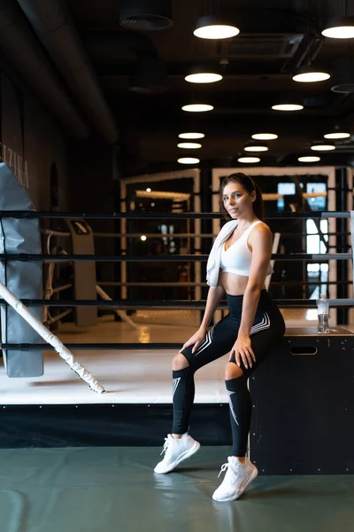 Sonriente chica en forma sosteniendo la toalla y descansando en el gimnasio . —  Fotos de Stock