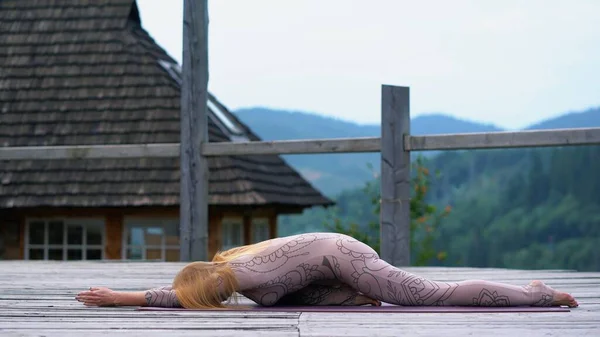 Žena ráno cvičí jógu na terase na čerstvém vzduchu. — Stock fotografie