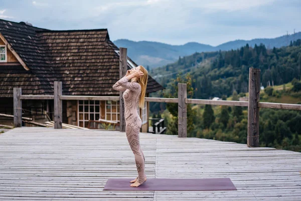 Eine Frau praktiziert morgens Yoga auf einer Terrasse an frischer Luft. — Stockfoto