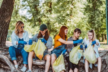 Bir grup aktivist arkadaş parkta plastik atık topluyor. Çevresel koruma.