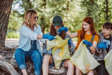 Bir grup aktivist arkadaş parkta plastik atık topluyor. Çevresel koruma.