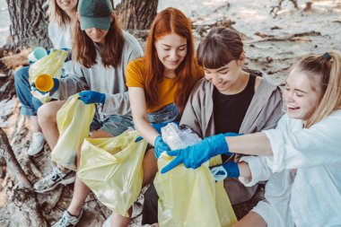 Bir grup aktivist arkadaş parkta plastik atık topluyor. Çevresel koruma.