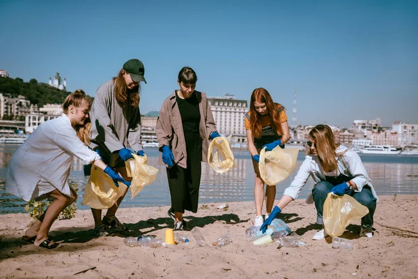 Ομάδα ακτιβιστών φίλοι μαζεύουν πλαστικά απόβλητα στην παραλία. Προστασία του περιβάλλοντος. — Φωτογραφία Αρχείου