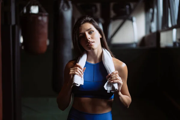 Sonriente chica en forma sosteniendo la toalla y descansando en el gimnasio . —  Fotos de Stock