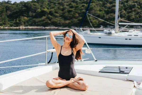Mujer joven sana y tranquila haciendo yoga en yate de vela en el mar en el fondo de la isla —  Fotos de Stock