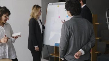 Beyaz tahtayla iş adamları toplantıda stratejiyi tartışıyor