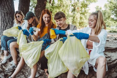 Bir grup aktivist arkadaş parkta plastik atık topluyor. Çevresel koruma.