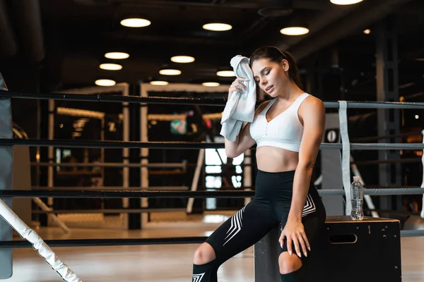 Senyum gadis fit memegang handuk dan beristirahat di gym. Gadis mengusap keringat dengan handuk — Stok Foto
