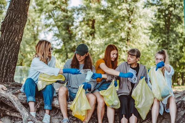 Bir grup aktivist arkadaş parkta plastik atık topluyor. Çevresel koruma.