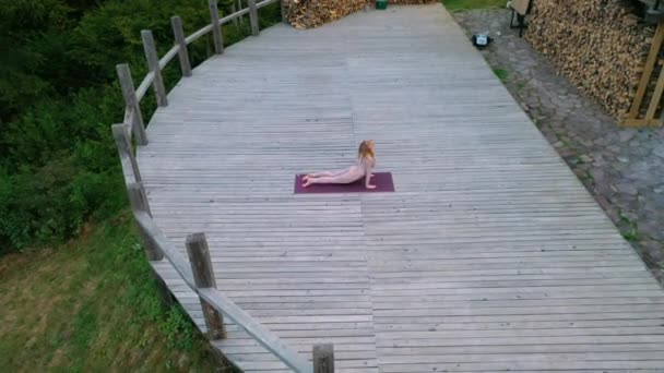 En kvinna utövar yoga på morgonen på en terrass på en frisk luft. — Stockvideo
