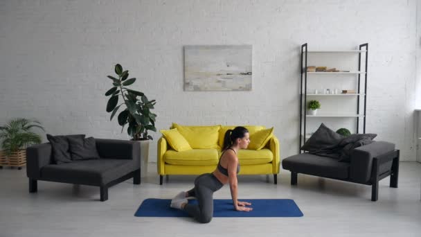 Красивая молодая женщина делает упражнения для живота на ковре в комнате — стоковое видео