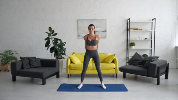 Vacker ung kvinna gör övningar för buken på mattan i rummet — Stockvideo