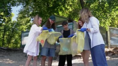 Bir grup aktivist arkadaş plajda plastik atık topluyor. Çevresel koruma.