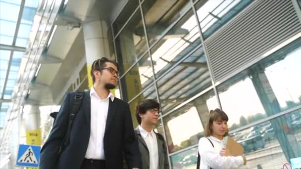 Equipo de negocios dos hombres y una mujer caminando juntos fuera . — Vídeo de stock