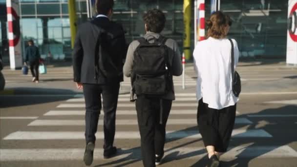 Two businessmen and woman walk across a road — Stock Video