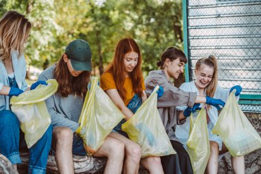 Bir grup aktivist arkadaş parkta plastik atık topluyor. Çevresel koruma.