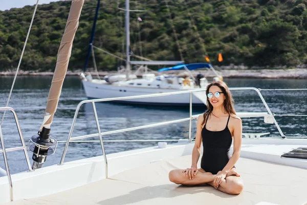 Sağlıklı ve sakin bir kadın, adanın arka planında, denizde yelkenli teknede yoga yapıyor. — Stok fotoğraf