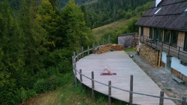 Een vrouw oefent 's morgens yoga op een terras op een frisse lucht. — Stockvideo