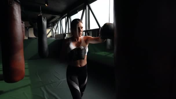 Молода жінка боксує в спортзалі, на темному тлі. Сильна і незалежна жіноча концепція — стокове відео