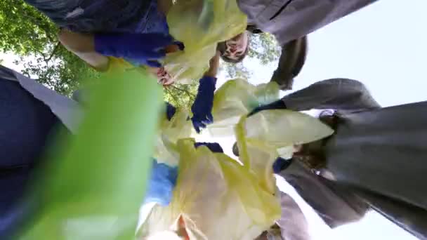 Ομάδα ακτιβιστών φίλοι πετάνε πολλά σκουπίδια σε μια τσάντα. Σκοποβολή από κάτω προς τα πάνω — Αρχείο Βίντεο