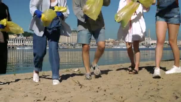 Grupo de ativistas amigos coletando resíduos de plástico na praia. Conservação do ambiente . — Vídeo de Stock