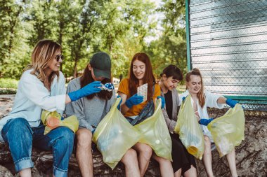 Bir grup aktivist arkadaş parkta plastik atık topluyor. Çevresel koruma.