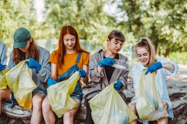 Bir grup aktivist arkadaş parkta plastik atık topluyor. Çevresel koruma.