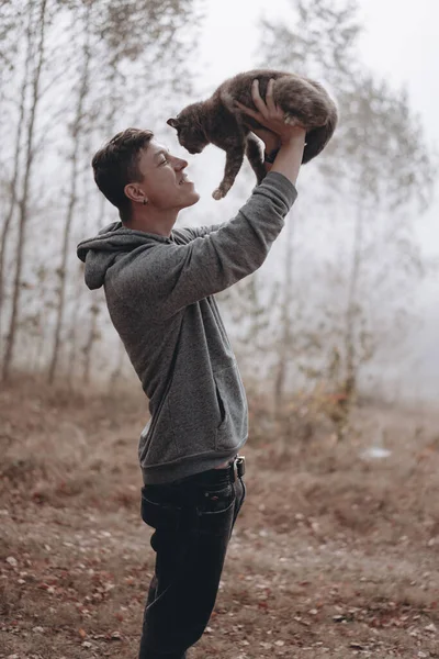 The guy holds a cat in the park. The park is shrouded in fog — Stock Photo, Image