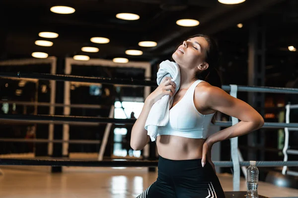 Chica sonriente en forma sosteniendo la toalla y descansando en el gimnasio. Chica limpia el sudor con una toalla — Foto de Stock