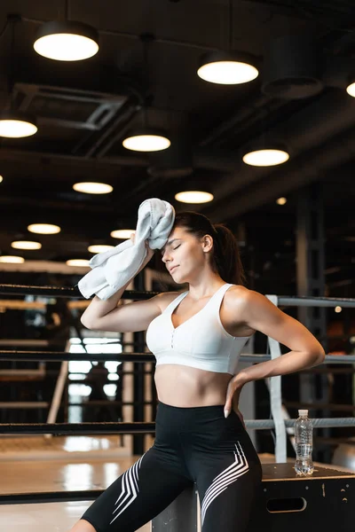 Chica sonriente en forma sosteniendo la toalla y descansando en el gimnasio. Chica limpia el sudor con una toalla — Foto de Stock