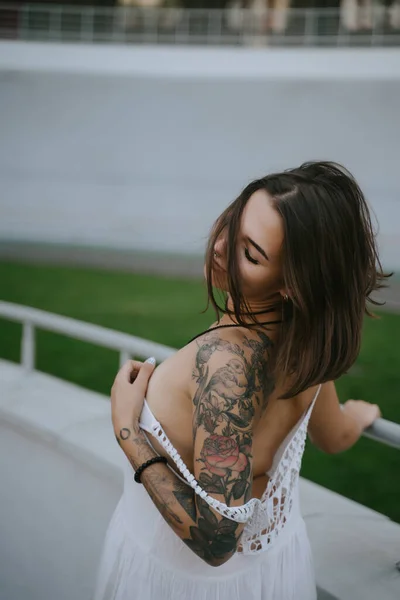 Sıska seksi kadın, beyaz bir elbise içinde arkasını gösteriyor, arkasını kolluyor. — Stok fotoğraf