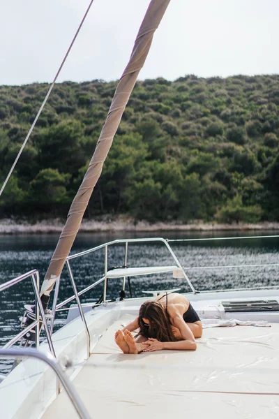 Fiatal egészséges és nyugodt nő csinál jóga vitorlás jacht hajó a tengeren a szigeten háttér — Stock Fotó