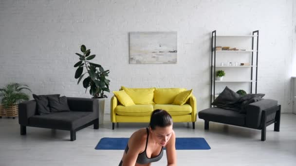 Beautiful young woman does exercises for the abdomen on the rug in the room — Stock Video