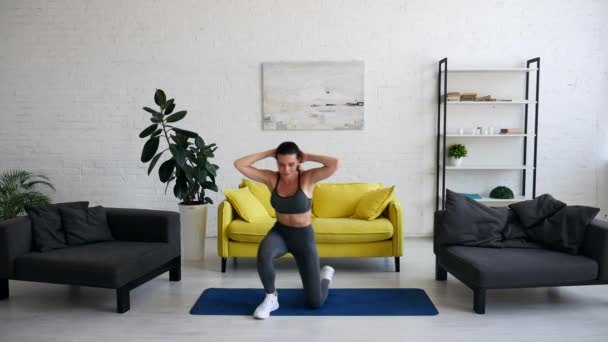 Όμορφη νεαρή γυναίκα κάνει ασκήσεις για την κοιλιά στο χαλί στο δωμάτιο — Αρχείο Βίντεο