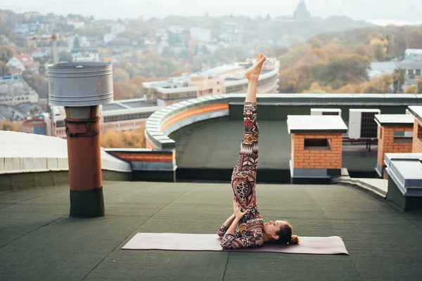 Mujer haciendo yoga en el techo de un rascacielos en la gran ciudad . —  Fotos de Stock