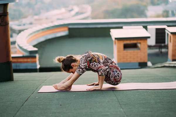 Mujer haciendo yoga en el techo de un rascacielos en la gran ciudad . —  Fotos de Stock