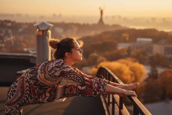 Vrouw doet yoga op het dak van een wolkenkrabber in de grote stad. — Stockfoto