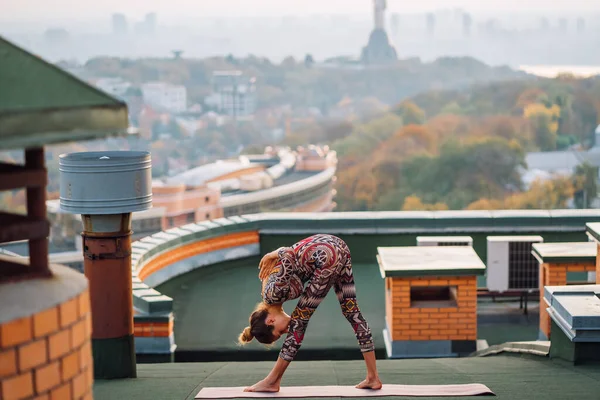 Mujer haciendo yoga en el techo de un rascacielos en la gran ciudad . —  Fotos de Stock