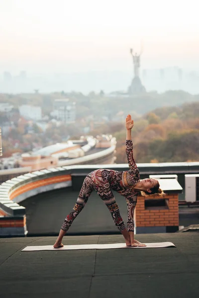 Mujer haciendo yoga en el techo de un rascacielos en la gran ciudad . —  Fotos de Stock