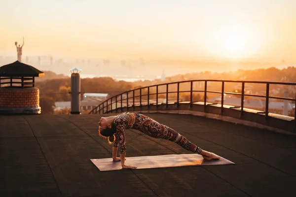 Mujer haciendo yoga en el techo de un rascacielos en la gran ciudad . —  Fotos de Stock