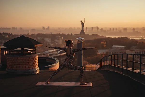 Mujer haciendo yoga en el techo de un rascacielos en la gran ciudad . —  Fotos de Stock