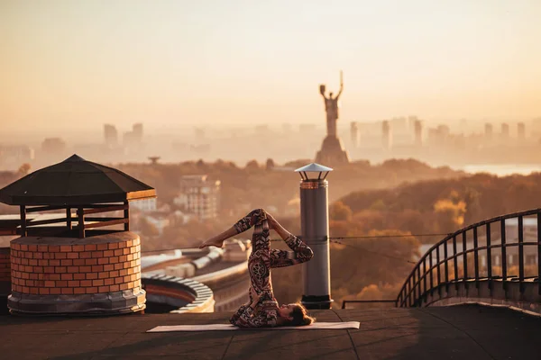 Mujer haciendo yoga en el techo de un rascacielos en la gran ciudad . —  Fotos de Stock