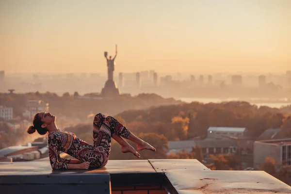 Mujer haciendo yoga en el techo de un rascacielos en la gran ciudad . —  Fotos de Stock