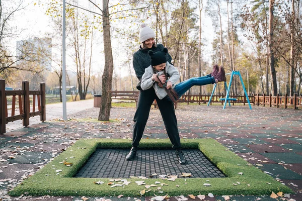 Annesi ve kızı sonbahar parkında trambolinde birlikte zıplıyorlar. — Stok fotoğraf