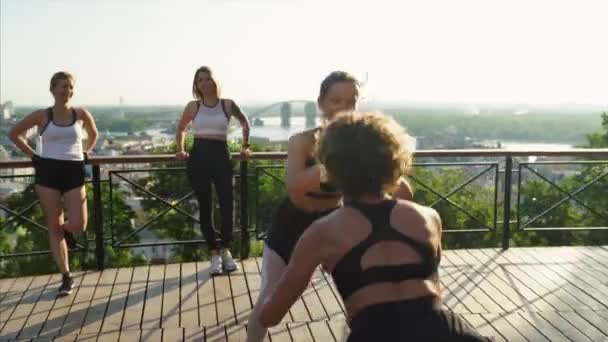 Sportmädchen im Hintergrund der Großstadt. Sportliche junge Frauen machen Morgengymnastik. — Stockvideo