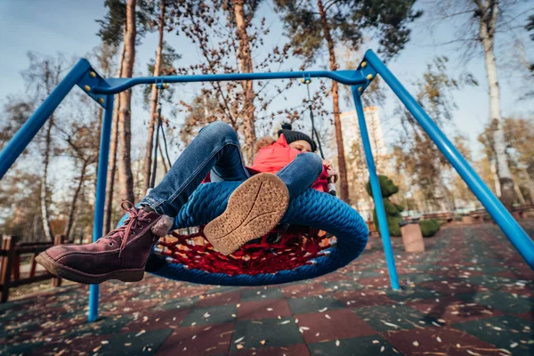 スイングして幸せな子供の女の子。秋のパックで遊んでいる小さな子供. — ストック写真