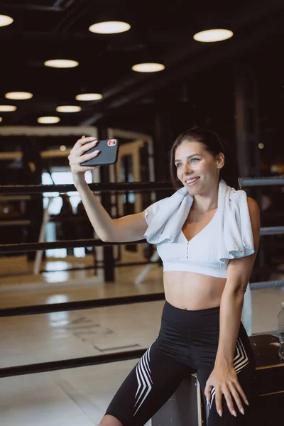 Mladá žena sportovní pořizování selfie s mobilním telefonem pro sociální sítě v tělocvičně. — Stock fotografie