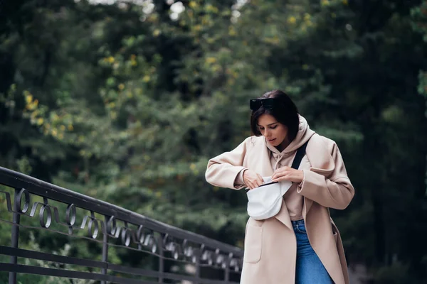 Jonge vrouw op zoek naar iets in haar tas tijdens de wandeling — Stockfoto