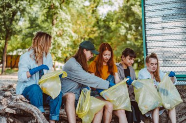 Bir grup aktivist arkadaş parkta plastik atık topluyor. Çevresel koruma.