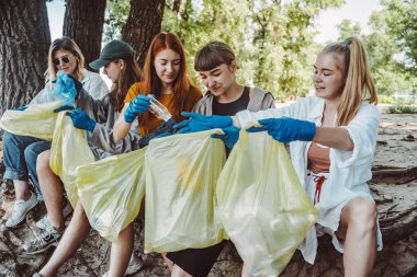 Bir grup aktivist arkadaş parkta plastik atık topluyor. Çevresel koruma.